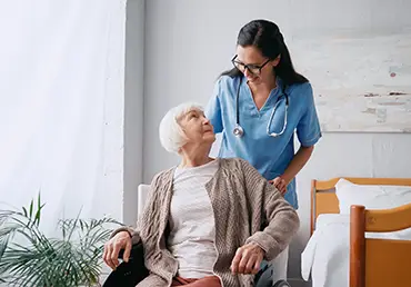 happy nurse in eyeglasses moving aged woman in wheelchair