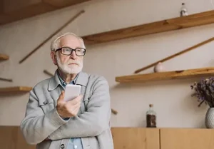 senior man contemplating with smartphone