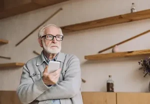 senior man contemplating with smartphone