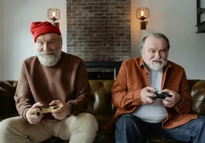 Two elderly gentlemen play video games together during retirement.