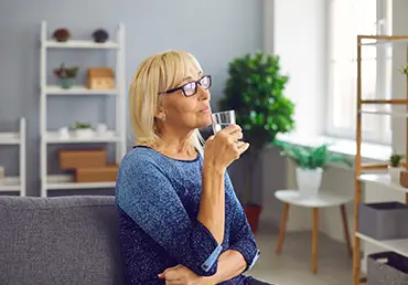 senior woman drinking a glass of pure fresh water to stay hydrated and healthy