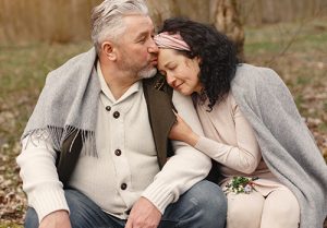 An elderly couple sitting down outside.
