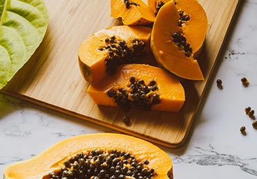 Papaya slices on a cutting board are seen.