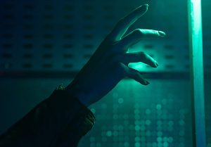 A hand reaches out toward an artificial light.