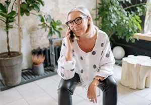 Cool older woman smiles while on the phone.