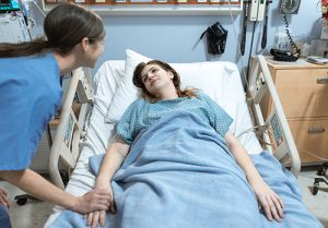 A nurse smiles at a hospital patient.