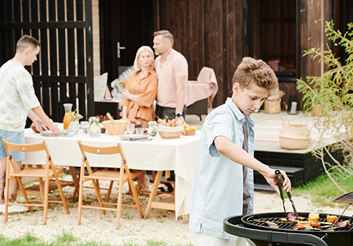 A family sets a table and prepares a barbecue meal.