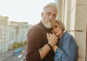 A senior couple holds hands on a balcony.