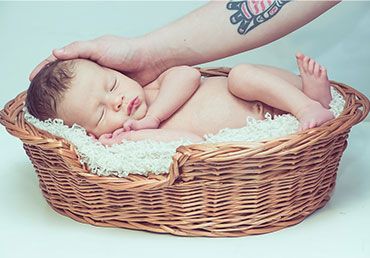 Photo of a baby in a cradle with a parent's hand