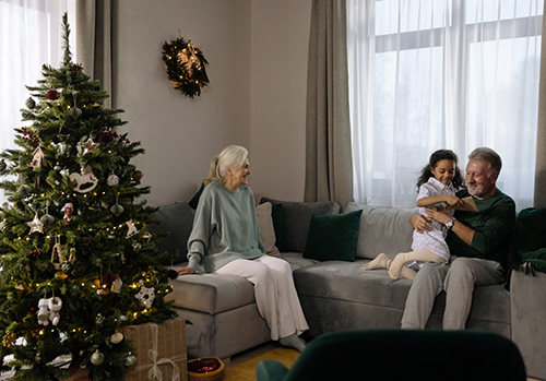 At Christmas, grandparents sit on a couch with their granddaughter.
