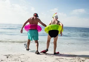 Older couple walks on beach enjoying their retirement.