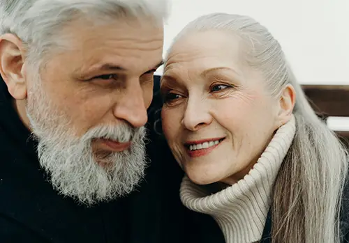 An elderly couple smiles together.