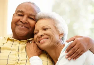 Older African American couple hugs.