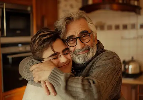 medicare aged man in a kitchen hugging his grandson