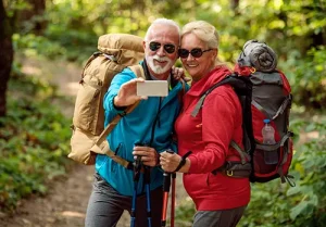 A senior husband and wife pose for a photo in the forest.