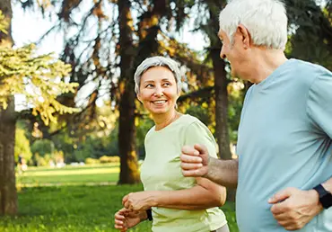 A senior couple exercises together in a park.