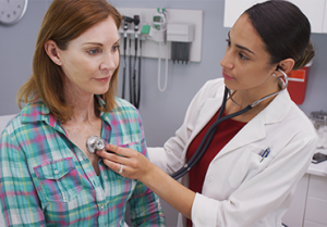 short term health coverage pros and cons woman and doctor at office performing check up on patient Thumbnail