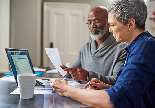 A senior couple busy reviewing documents in the home together.