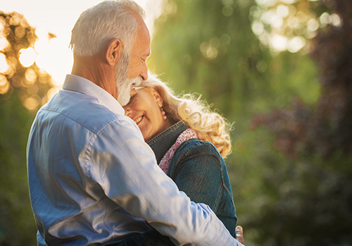 A happy senior couple embraces in the park.