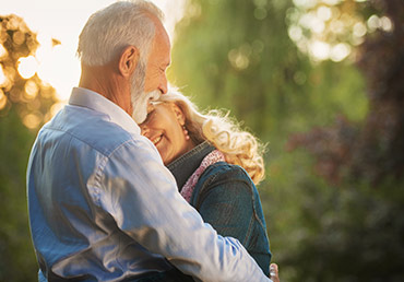A happy senior couple embraces in the park.