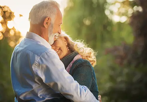 A happy senior couple embraces in the park.