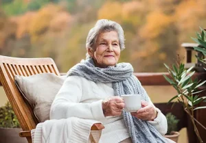 Elderly woman sitting with coffee and thinking