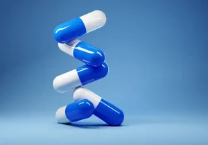 A stack of antibiotic pill capsules on a blue background.