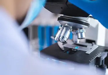 Scientist examining liquid biopsy under microscope