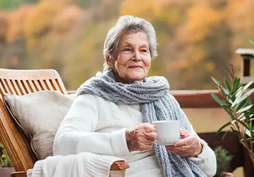 Elderly woman sitting with coffee and thinking