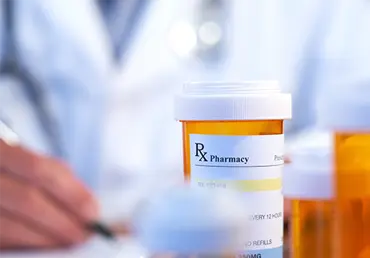 Prescription drug bottle on table with pharmacist in background