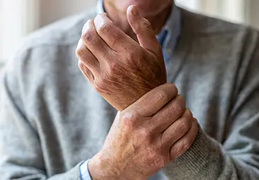 Senior man with arthritis rubbing hands